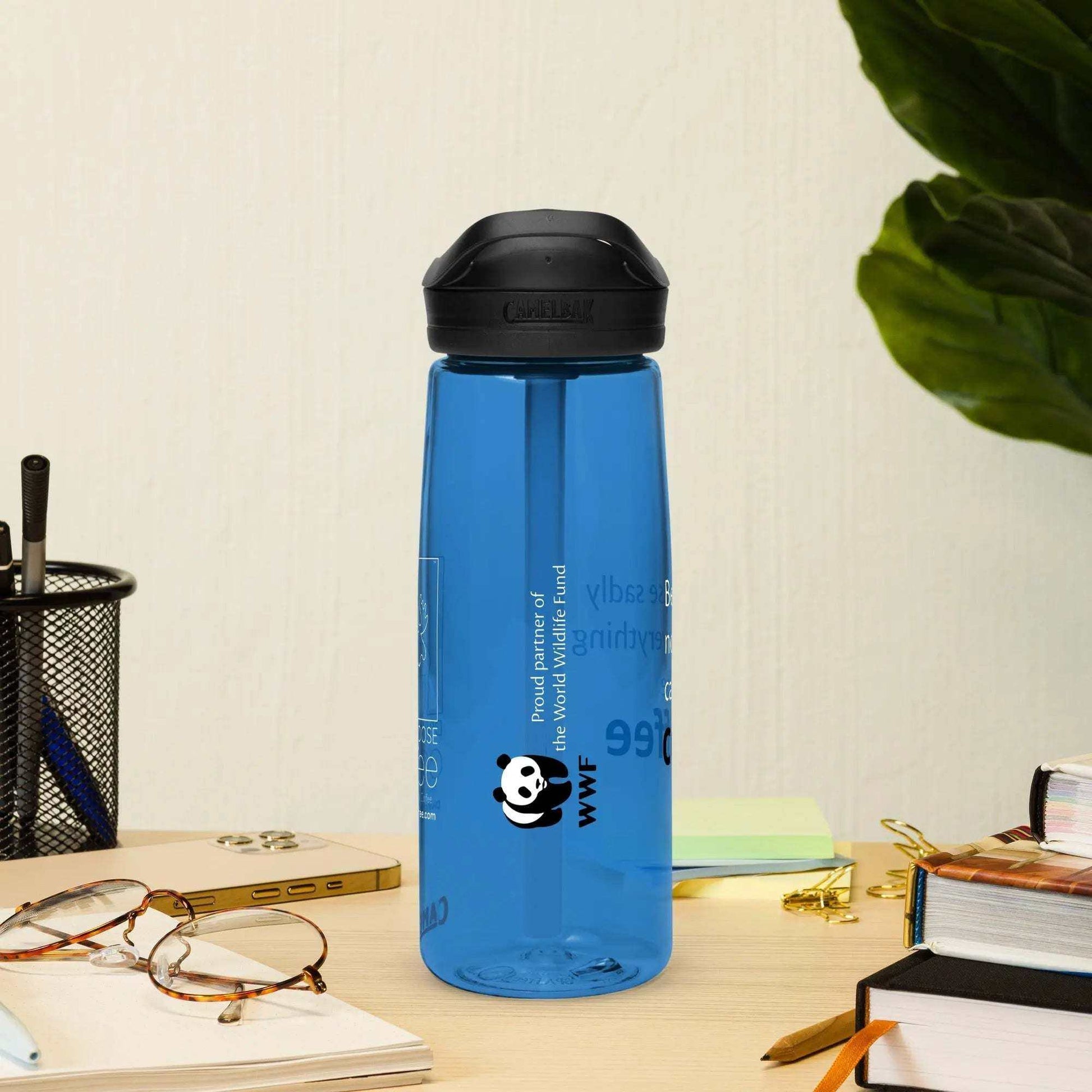 Blue CamelBak Eddy+ Water Bottle made from 50% recycled plastic with spill-proof lid and bite valve on desk next to glasses and books